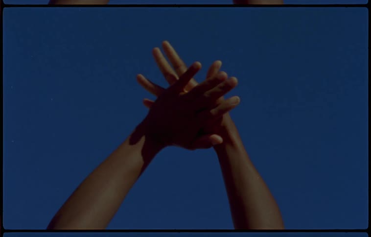 A woman is holding her hands together outdoors