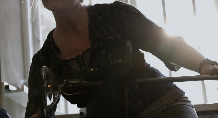 A female glass artisan crafts a piece of glass