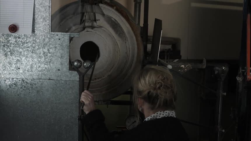 A glass artisan is lighting her oven
