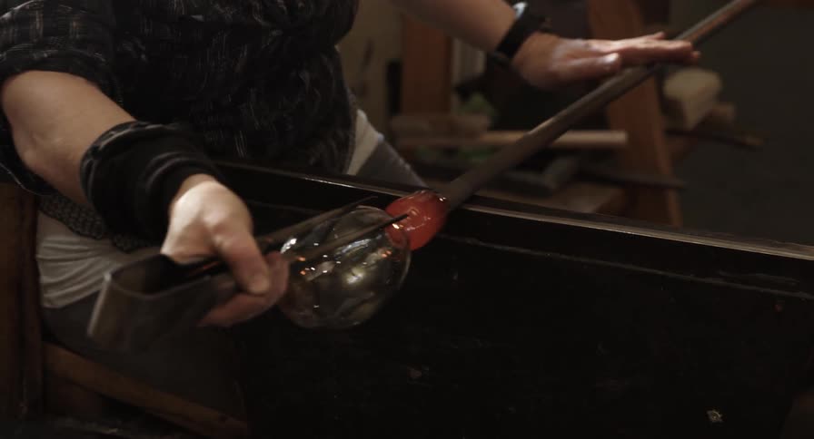 A person is spinning glass with tools