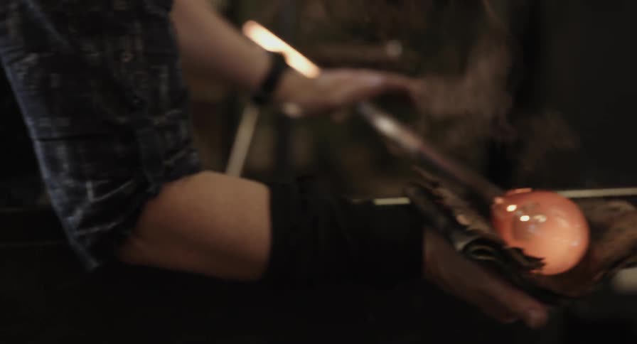 A person rolls molten glass