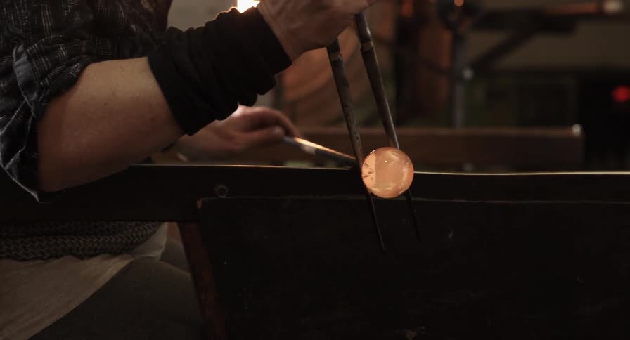 A person is spinning glass with tools