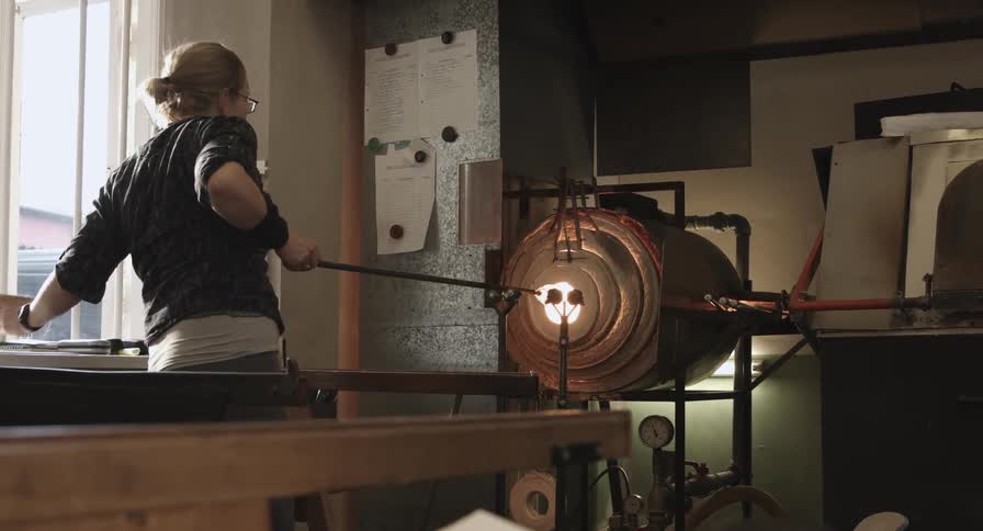 A woman is heating glass in an oven