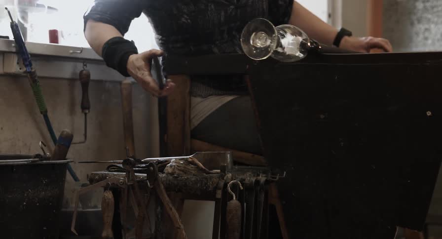A glass artisan aligns the bottom of a wine glass