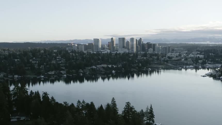 Reveal of homes along a tree lined Medina neighborhood with downtown Bellevue in the distance