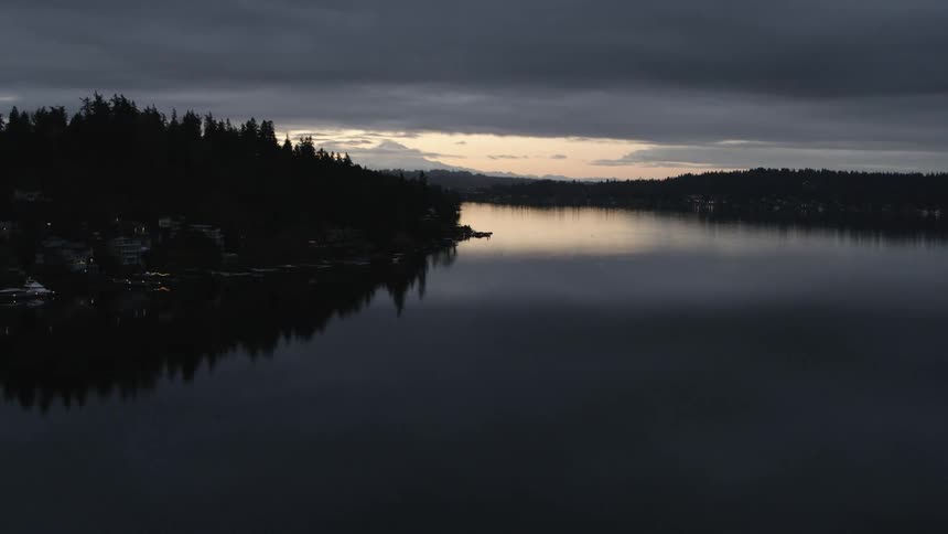 Mount Rainier peeks out from behind a Bellevue hillside neighborhood along Lake Washington at sunrise