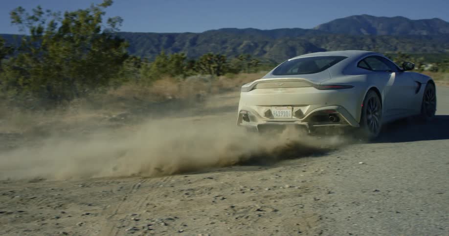 A car is driving outdoors on a dirt road in spring