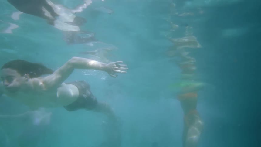 A man and two women swimming in the water with bubbles