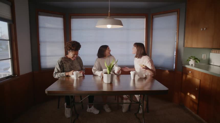 A group of friends sitting in a table at home talking and laughing
