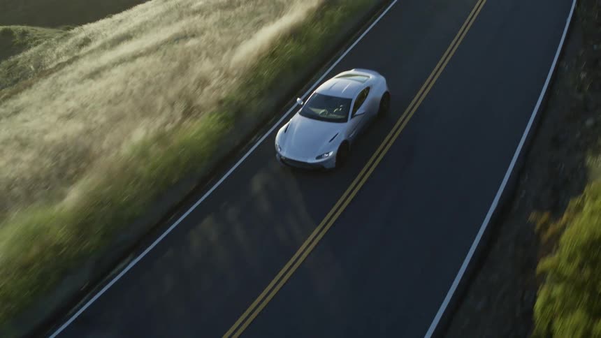 An aerial view of a car driving along a road in the hills
