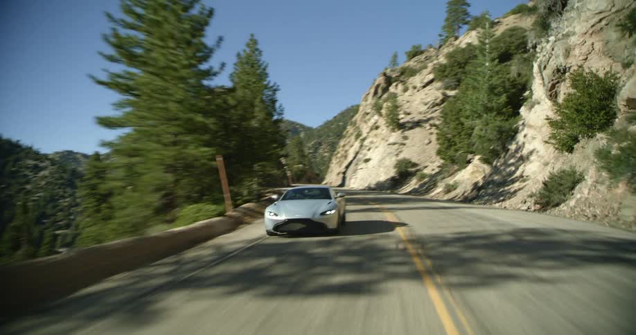 A car driving on a road with hills trees the sky and clouds in the background