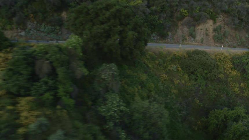 A car driving on a road with hills trees the sky and clouds in the background
