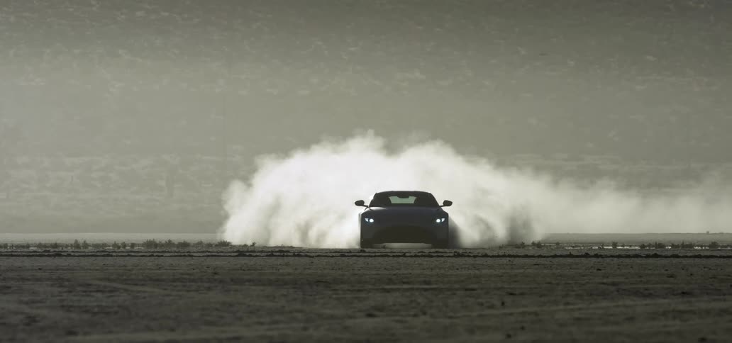 Sports car leaving a dust trail while driving on the desert at sunset