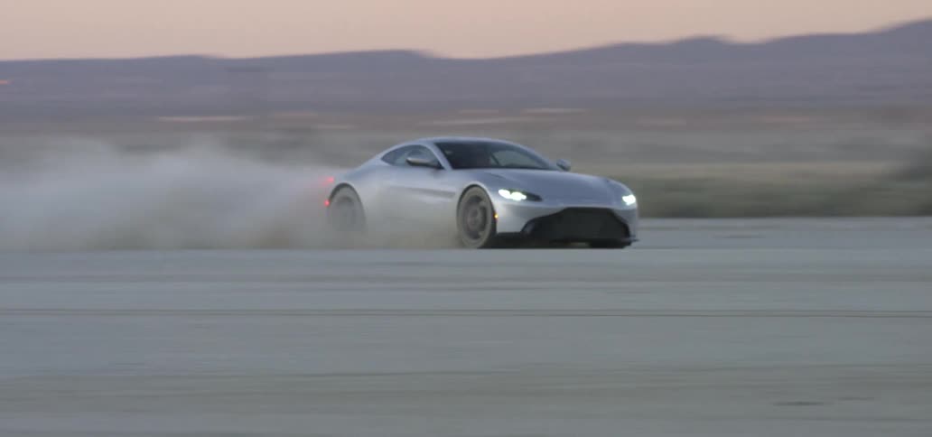 Sports car leaving a dust trail while driving on the desert at sunset