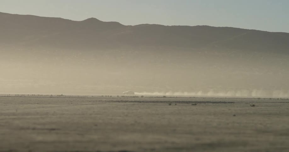 Truck rides across a desert near a mountain ridge