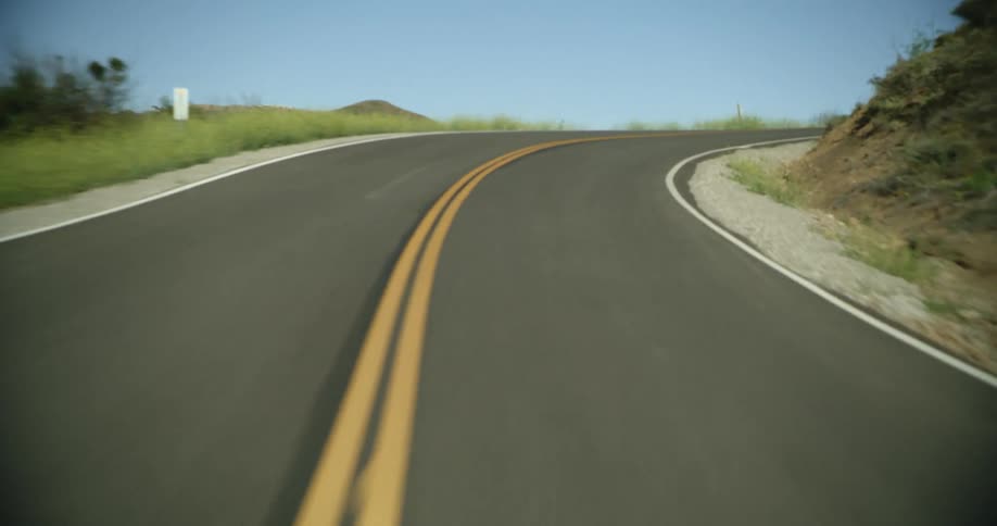A point of view of driving on a highway next to mountains with a cliff side at daytime