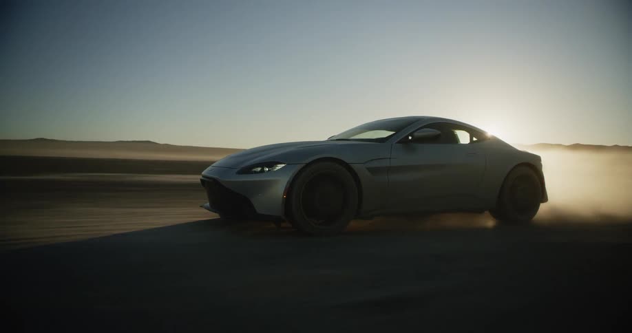 Sports car leaving a dust trail while driving on the desert at sunset