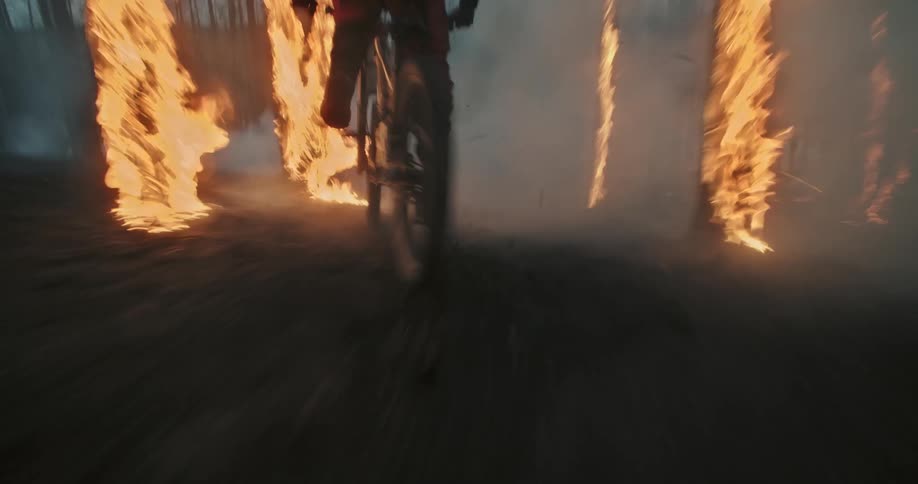 Mountain biker skids into frame though ember pile and camera travels with him.