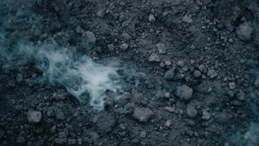 Smoke rising from smoldering ashes on the ground