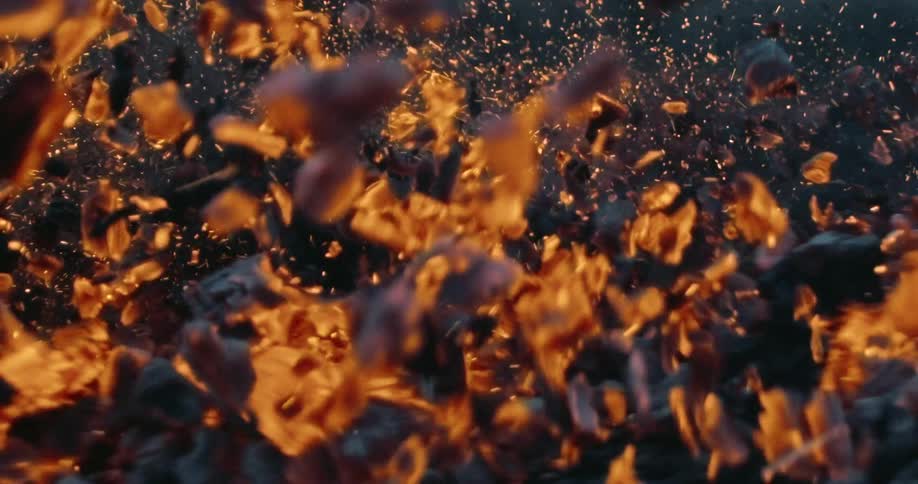 Burning ashes and embers fly into the air as foot drags through them.