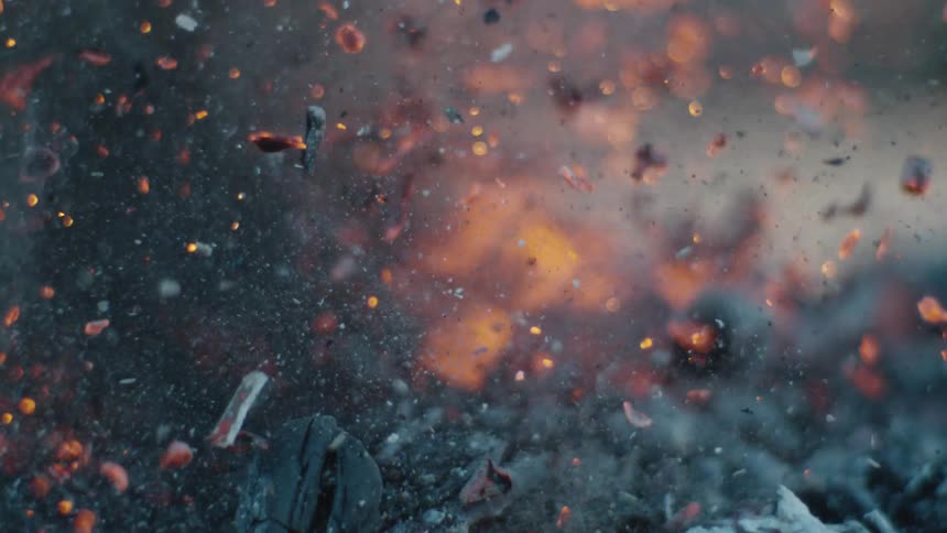 Smoke and embers rise from burning charred wood