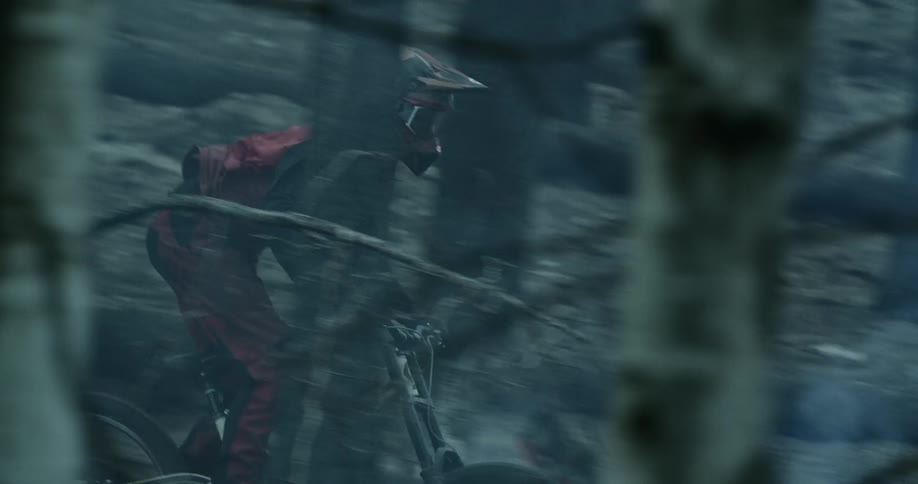 A young man driving a mountain bike over the ashes on a burning forest