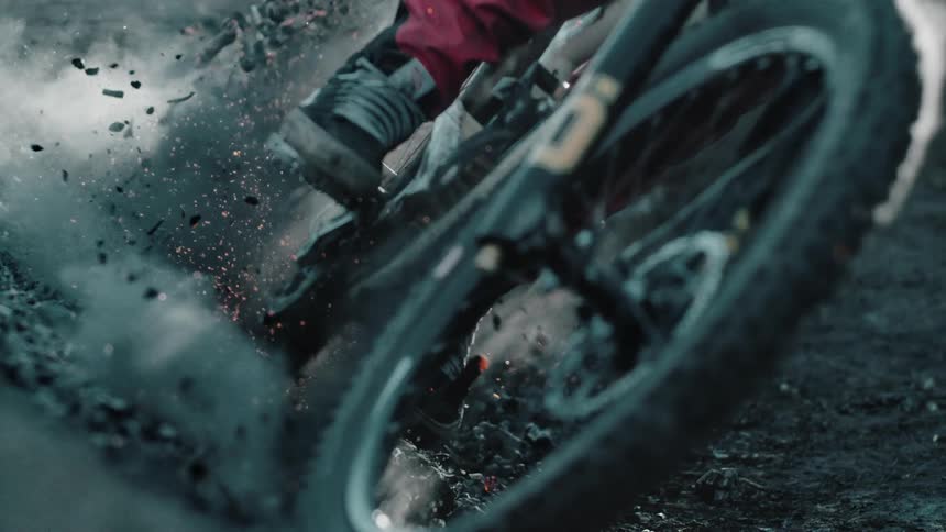 A cyclist kicks up dirt and ash while riding around a berm corner.