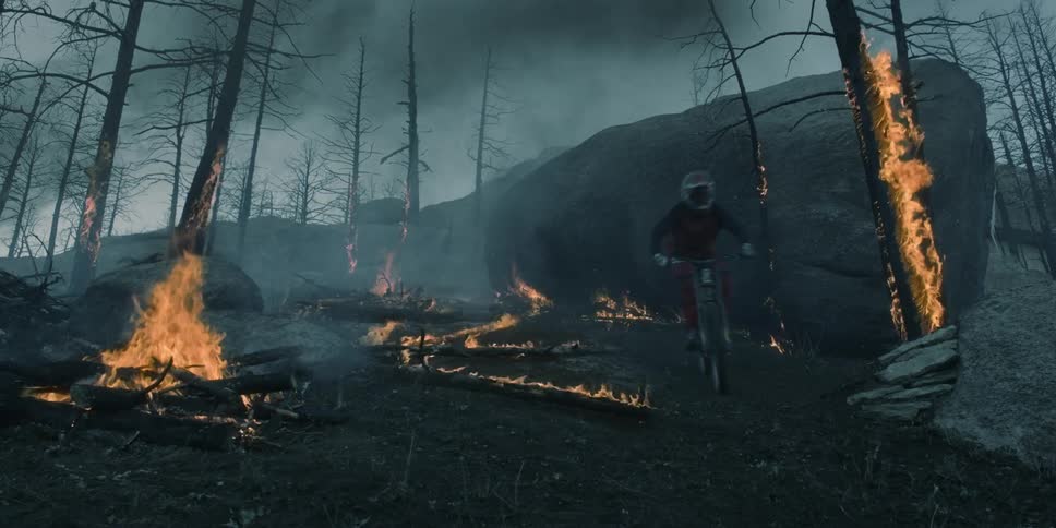A person on a mountain bike rides on a boulder over the forest fire
