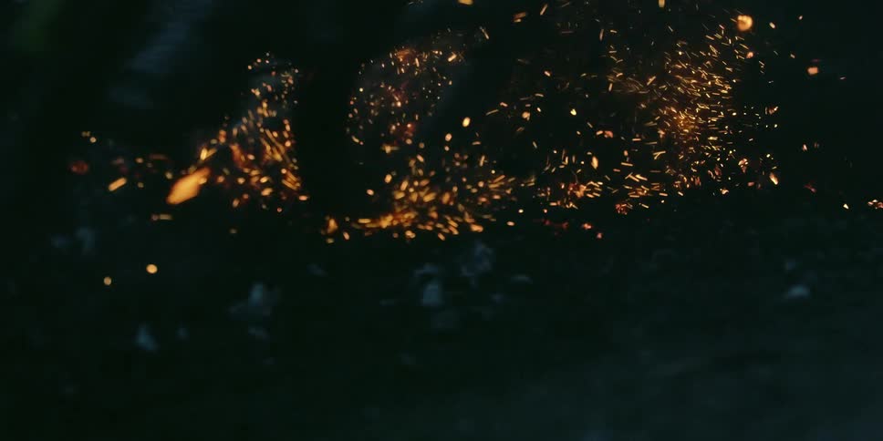 A bike riding over and kicking up ashes and embers on the ground