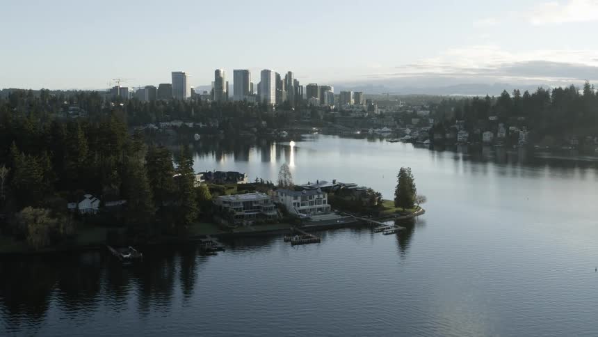 Sunrise ascending reveal of Meydenbauer Bay and downtown Bellevue from behind stunning lakeside homes