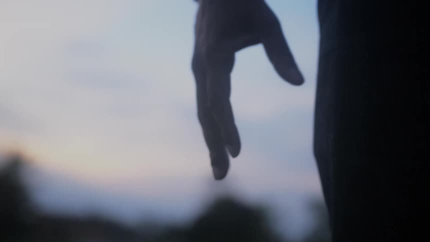 A man standing outside clenches his fist