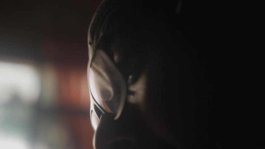 Close up of the face of a man wearing glasses in a room