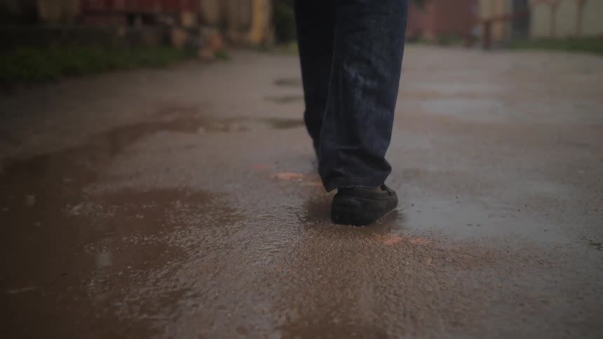 Close up of someone walking outdoors down a pathway in the rain