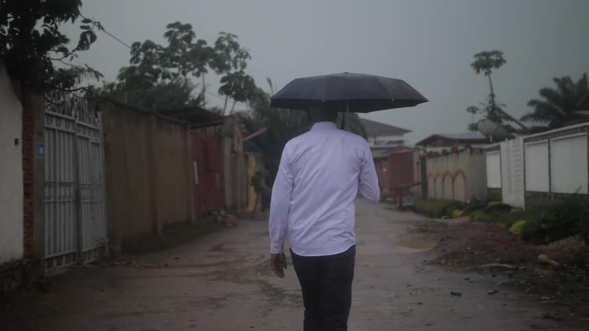 A man is carrying an umbrella as he walks down the alley