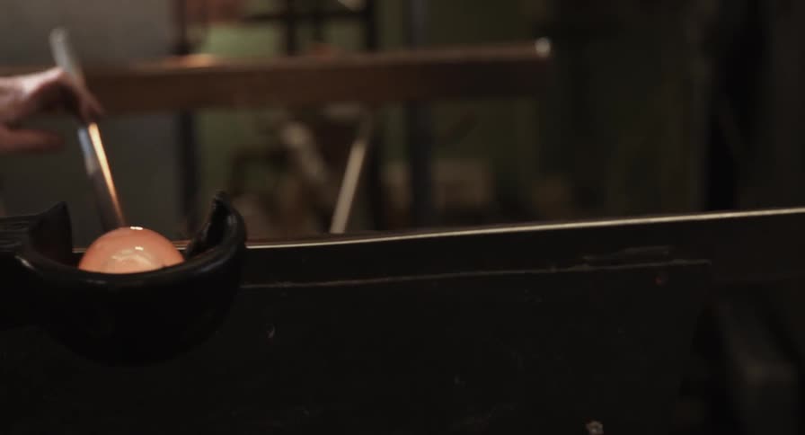 An artisan twirls a rod with glass on it to shape the glass