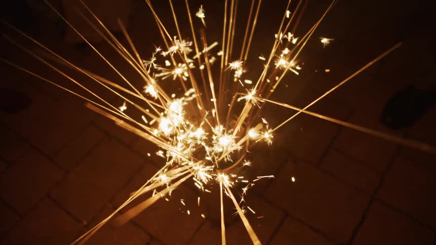Sparklers burnign inside a vase on the floor in a dark room