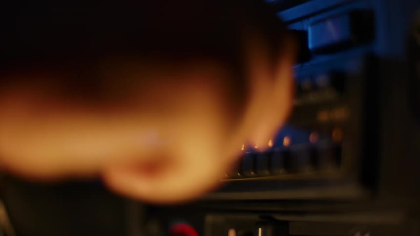 A person puts a cassette in a radio on a car dashboard