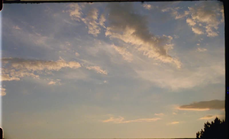 Strands of clouds in the yellowing daytime sky