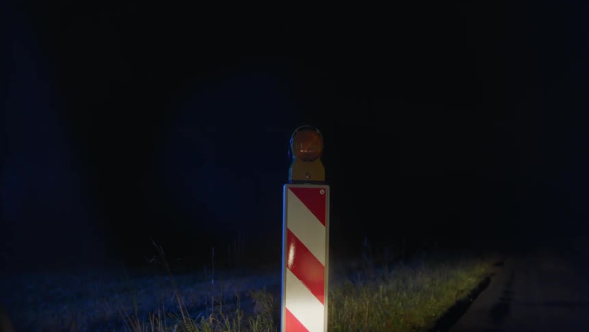 The cone on the side of the road has a flashing yellow light