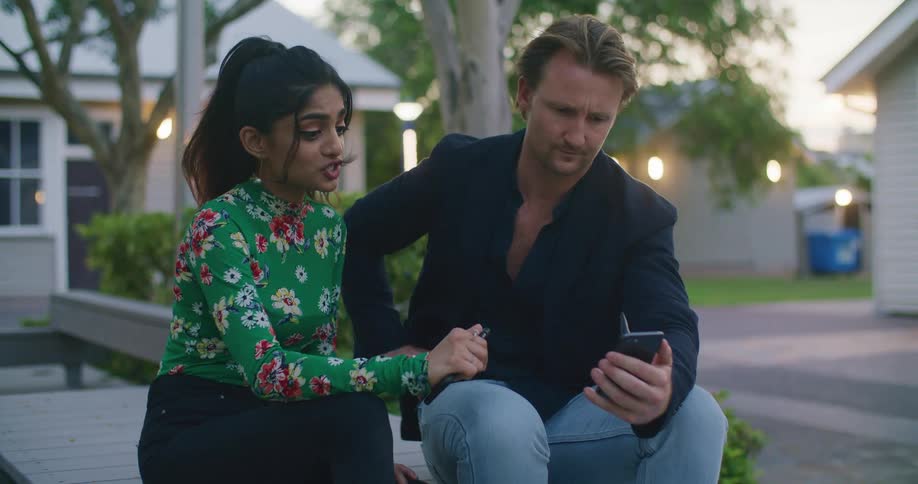 A man and woman looking at a smartphone talking
