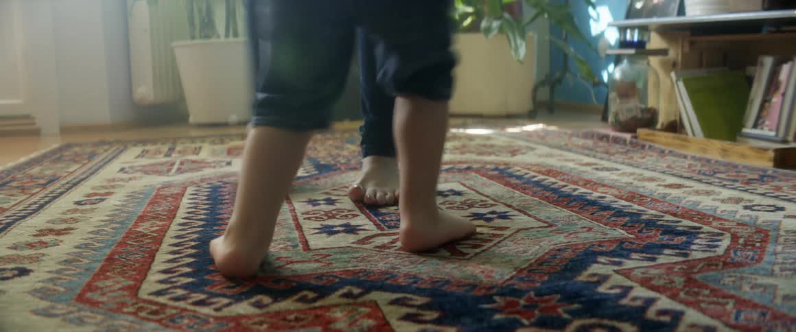 Adult spins a toddler around as the toddler jumps up and down on a carpet