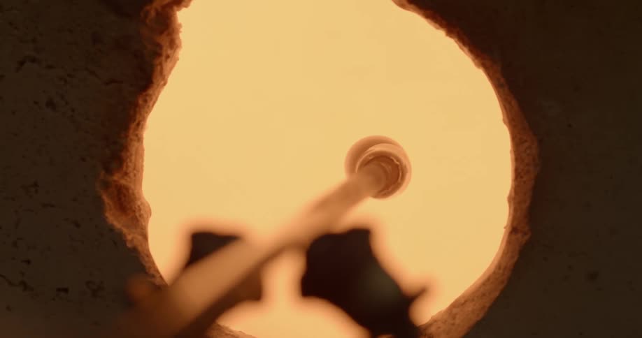 A lump of molten glass on the end of a rod turning in a kiln