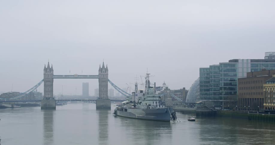 Ship floats on river near bridge tugboat and city waterfront with fog on the horizon