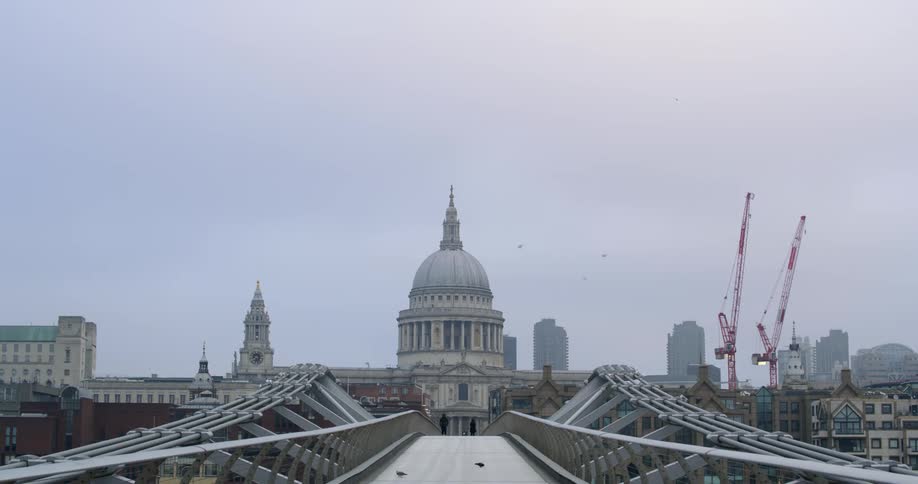 Fog covers skyline as pedestrians cross bridge leading to domed government building