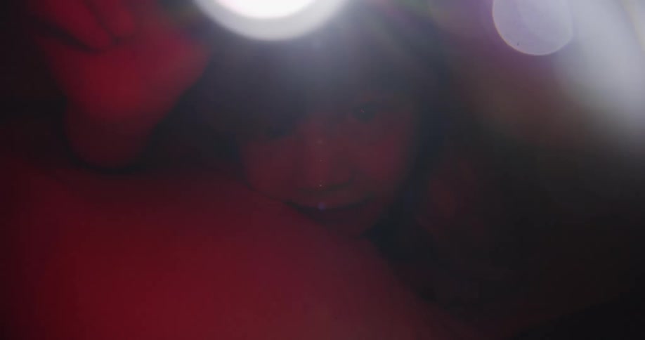 A child is waving a flashlight under the covers