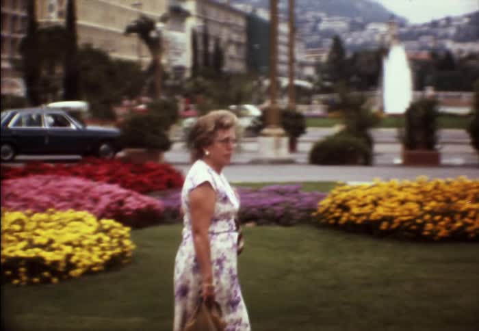 A woman in a floral dress walking in a city park on a summer day