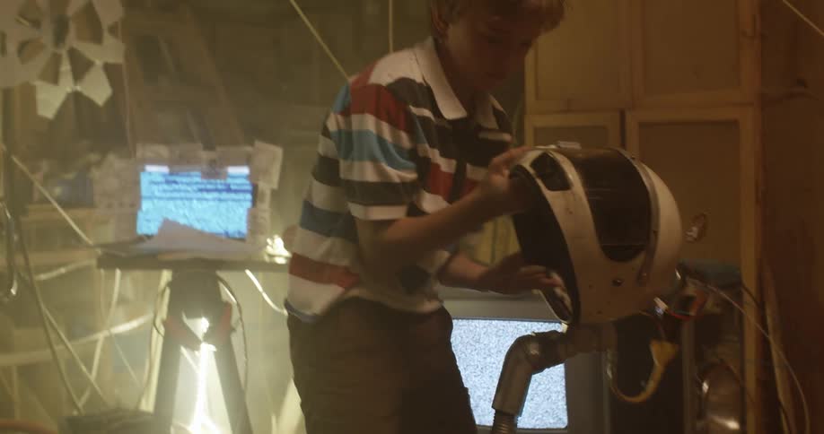 Young boy playing in the attic wearing an astronaut helmet