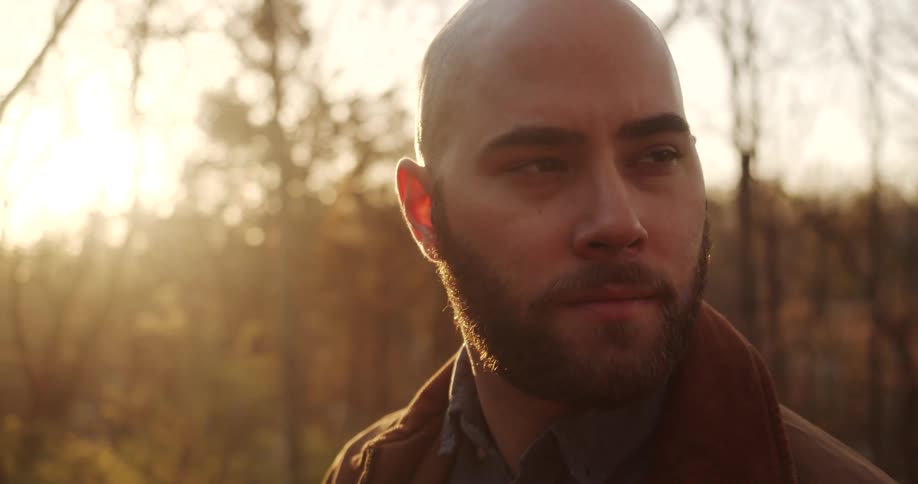 A man is standing by the woods at sunrise