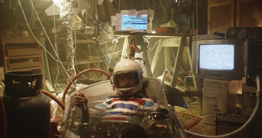 Young boy wearing an astronaut helmet plays inside a bathtub in the attic