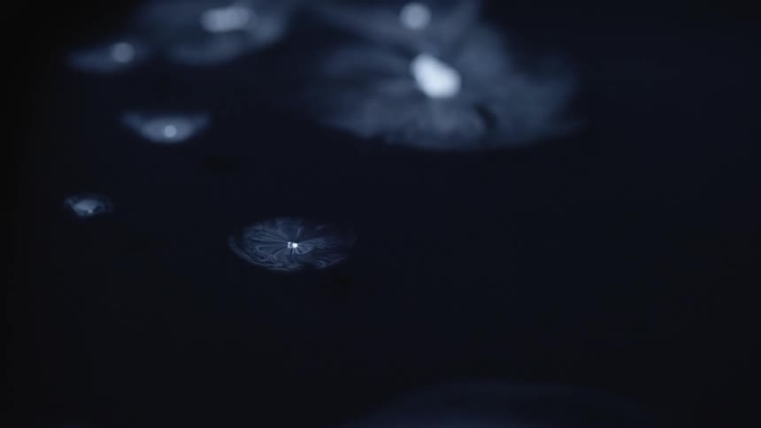 White glowing light points with wisps of white smoke against black
